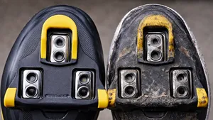 lose-up van een nieuwe en een versleten Shimano SPD-SL schoenplaat op de onderkant van een wielerschoen, naast elkaar.