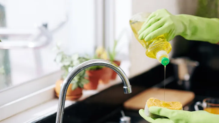 Woman pouring dish soap on sponge