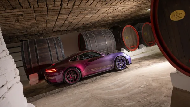  Een op maat gemaakte paarse Porsche 911 GT3 Touring geparkeerd in de ondergrondse wijnkelders van Cricova, naast grote houten wijnvaten.