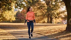 Happy athletic woman taking a walk through autumn park.