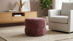 Bordeauxrode velvet opbergpoef Bubbles van Xenos in een modern Scandinavisch interieur met beige fauteuil en houten dressoir.