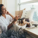 Young woman applying natural organic essential oil on hair and s