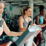 Group of athletes exercising on cross trainer while working out in gym.