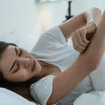 Asian young woman scratch hand feel suffer from allergy while sleeping. Beautiful attractive girl lying on bed in bedroom suffering from itching arm skin allergic reaction to insect bites, dermatitis.