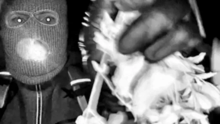 De gewapende man met skimasker bij de woning.