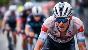 Vermoeide wielrenner raakt het wiel kwijt in het peloton tijdens de koers, gezicht vertrokken van inspanning in het tweede uur.