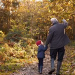 Grandfather And Granddaughter Enjoying Autumn Walk