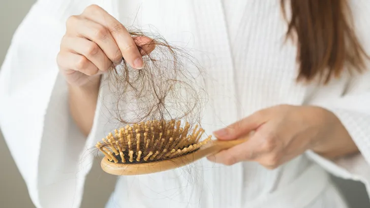 Vrouw haalt haren uit haar haarborstel