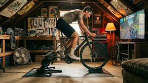 Een wielrenner traint fanatiek op een bewegende smart trainer, waarbij motion blur het voor- en achteruit glijden van de fiets in de 'pain cave' benadrukt.