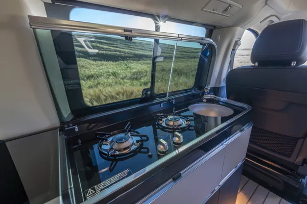 Binnenzijde van de Marco Polo met compacte keukenunit, kookpitten en werkblad, ideaal voor koken tijdens het kamperen.