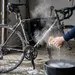 Een wielrenner maakt een zeer vieze racefiets vol pekel schoon met dampend heet water in een winterse garage.