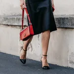 Milan, Italy - June, 19, 2022: woman wears high heels from Prada and logo Plaque detail shoulder bag In Scarlet