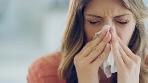 Shot of an attractive young woman feeling ill and blowing her nose with a tissue at home