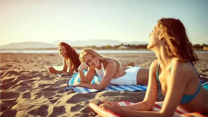 Drie vrouwen die op het strand genieten van de zon