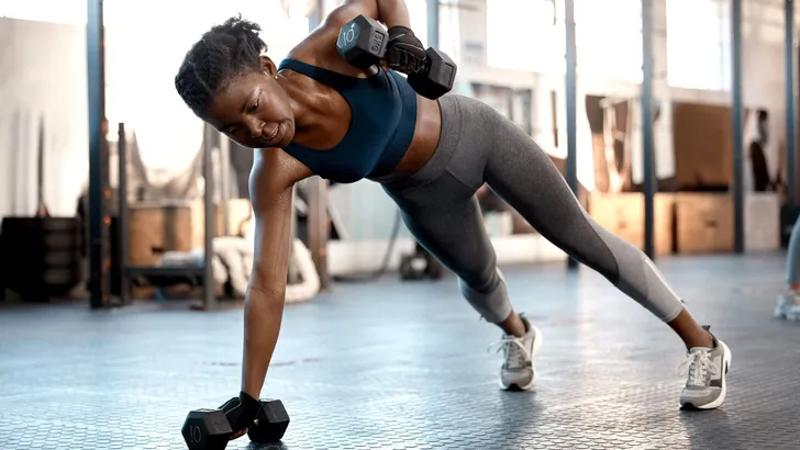Shot of a sporty young woman exercising with dumbbells in a gym