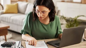Documents, finance and woman with laptop in home office for debt budget, taxes and remote work. Freelance, accounting and female online for savings, review or analysis, development or business growth