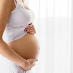 Pregnant woman standing next to window