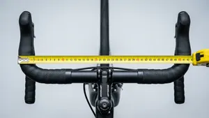 Bovenaanzicht in een studio van een racefietsstuur met een geel meetlint uitgetrokken over de breedte van het stuur.