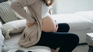 Cropped shot of Asian pregnant woman touching her belly and lower back, suffering from backache. Pregnancy health, wellbeing concept