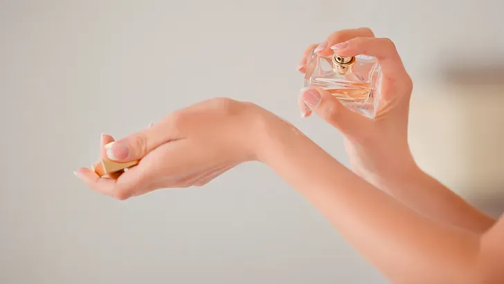 Een vrouw die parfum aanbrengt op haar pulse point; haar pols
