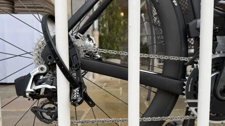 Close-up van een compact, zwart 'tiewrap'-stijl fietsslot vasthoudt om de kleine omvang en het driecijferige combinatieslot te laten zien.