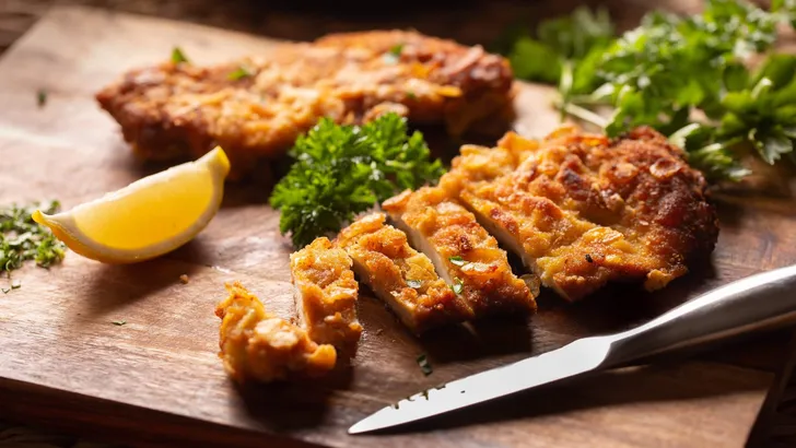 Traditional Viennese chicken Schnitzel on a wooden board.
