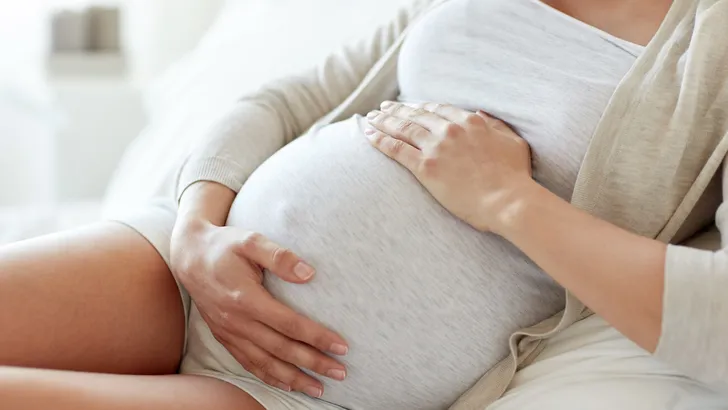 close up of pregnant woman lying in bed at home