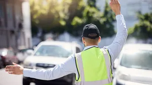 Rearview shot of a traffic warden guiding vehicles outdoors