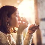 Woman holding hand mirror and fixing make-up.