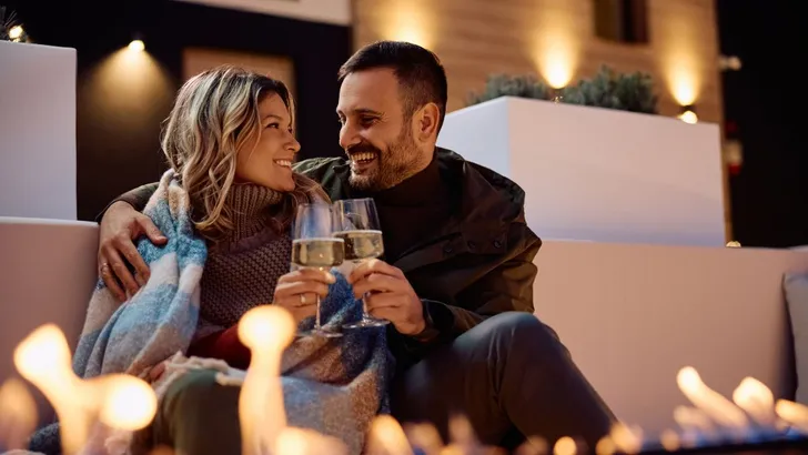 Man en vrouw proosten bij de buitenhaard.