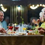 A group of family friends, comprising a young grandson and older individuals, share a delightful dinner in a modern restaurant, exemplifying the concept of healthy aging through intergenerational bonding and a joyous dining experience