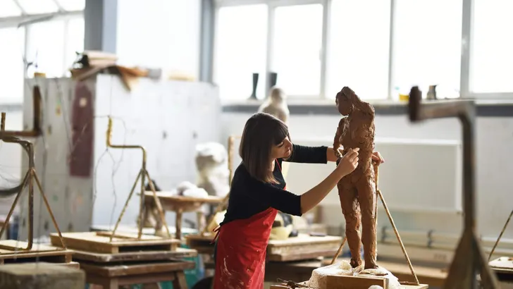 Young Female Sculptor is working in her studio