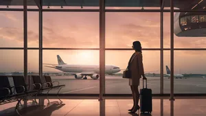 Young woman at the airport window looking to the planes