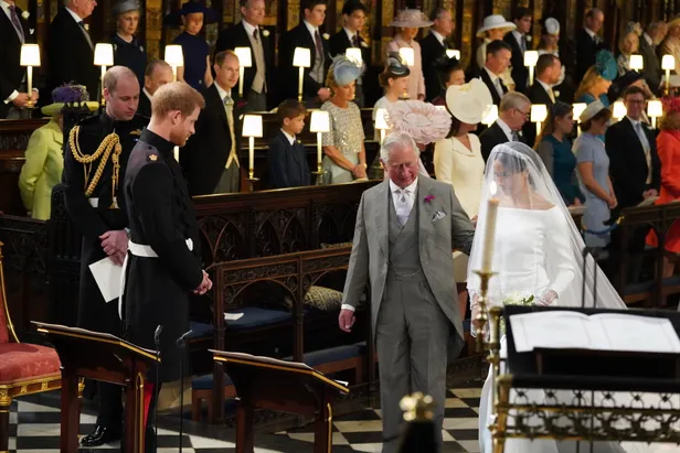 Prins Harry die verliefd zijn bruid Meghan bekijkt terwijl ze wordt vergezeld door koning Charles (Beeld: NL Beeld) 