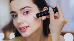 Close up van vrouw die Merit concealer gebruikt op haar gezicht.
