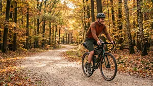 Een ontspannen mannelijke gravelbiker fietst met een helm op over een breed zandpad op de Veluwe.