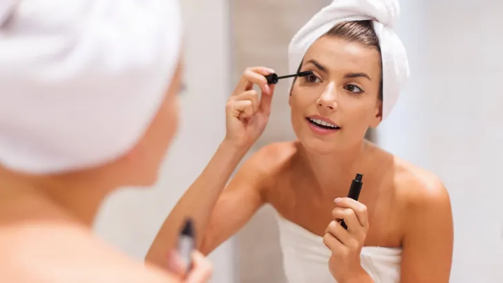 Beautiful woman using mascara in bathroom