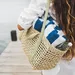 Vrouw met rieten strandtas met gestreepte handdoek erin - HEMA strandtas