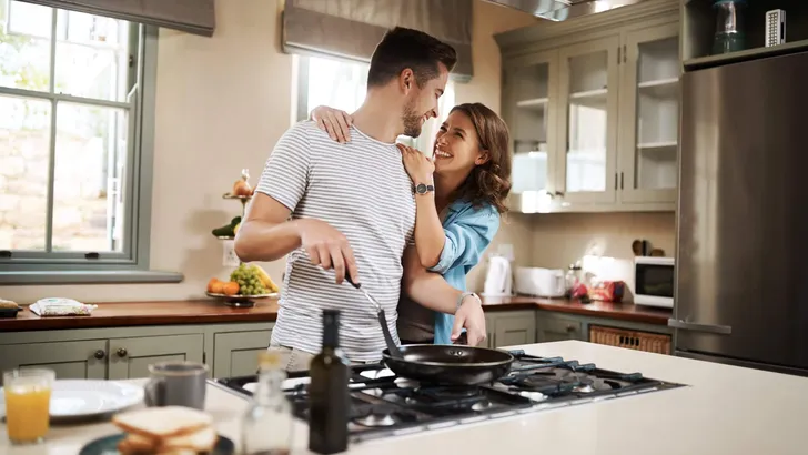 Love, food and cooking with couple in kitchen and hugging for breakfast, morning and happiness. Smile, care and nutrition with man and woman eating at home for happy, health and hungry together