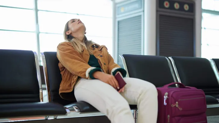 Bored woman, airport and luggage waiting with passport for missed flight, travel or vacation journey in Cape Town. Female traveler sitting in wait for delay departure, boarding plane or immigration