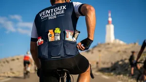 Close-up van de achterzakken van een wielrenner, gevuld met sportvoeding, met op de achtergrond de klim van de Mont Ventoux.