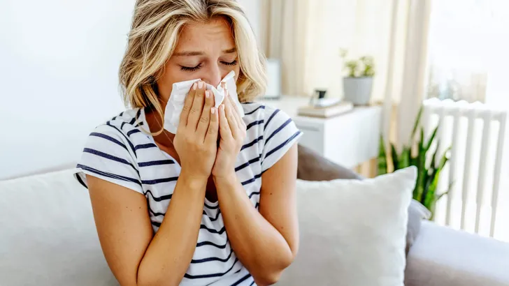 Shot of an attractive young woman feeling ill and blowing her no