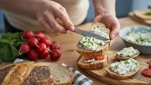 Vrouw maakt een sandwich met huttenkase en verse kruiden.