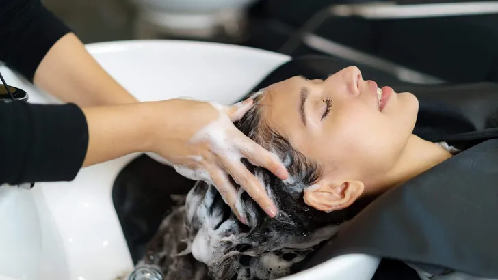 hairdresser is applying shampoo and massaging hair of a customer