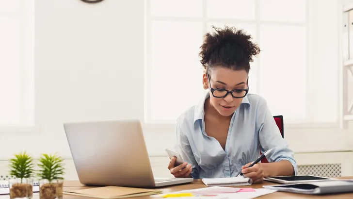 Smiling woman taking notes at office