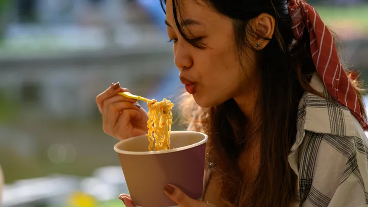 Young Asian woman eating instant noodles morning