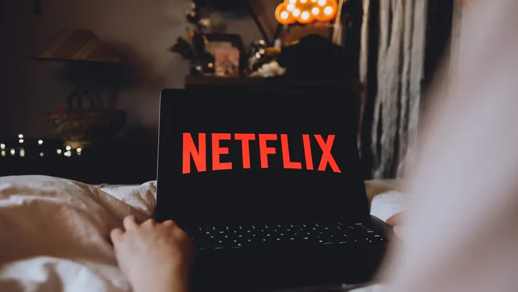 Netflix logo on the laptop screen. Young woman watching netflix channel sitting at home in the evening. Rostov-on-Don, Russia. 26 March 2020