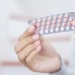 Woman hands opening birth control pills in hand. Eating Contraceptive Pill.