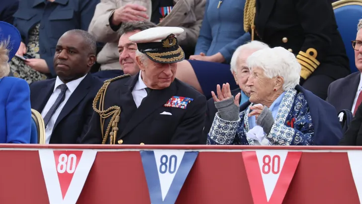 Charles zit naast Sarah McCorquodale op tribune tijdens VE day