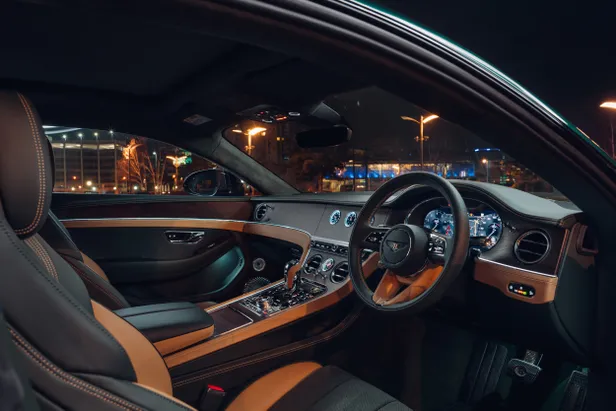 Interieur van de Bentley Continental GT S met leren stoelen, houtafwerking en digitaal dashboard